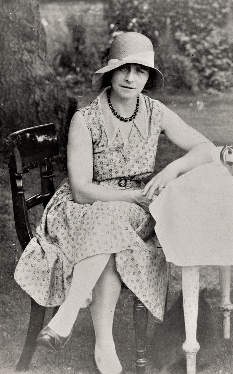 Vintage photo of a lady sat on a chair in a dress and hat as an example of biography writing and publishing